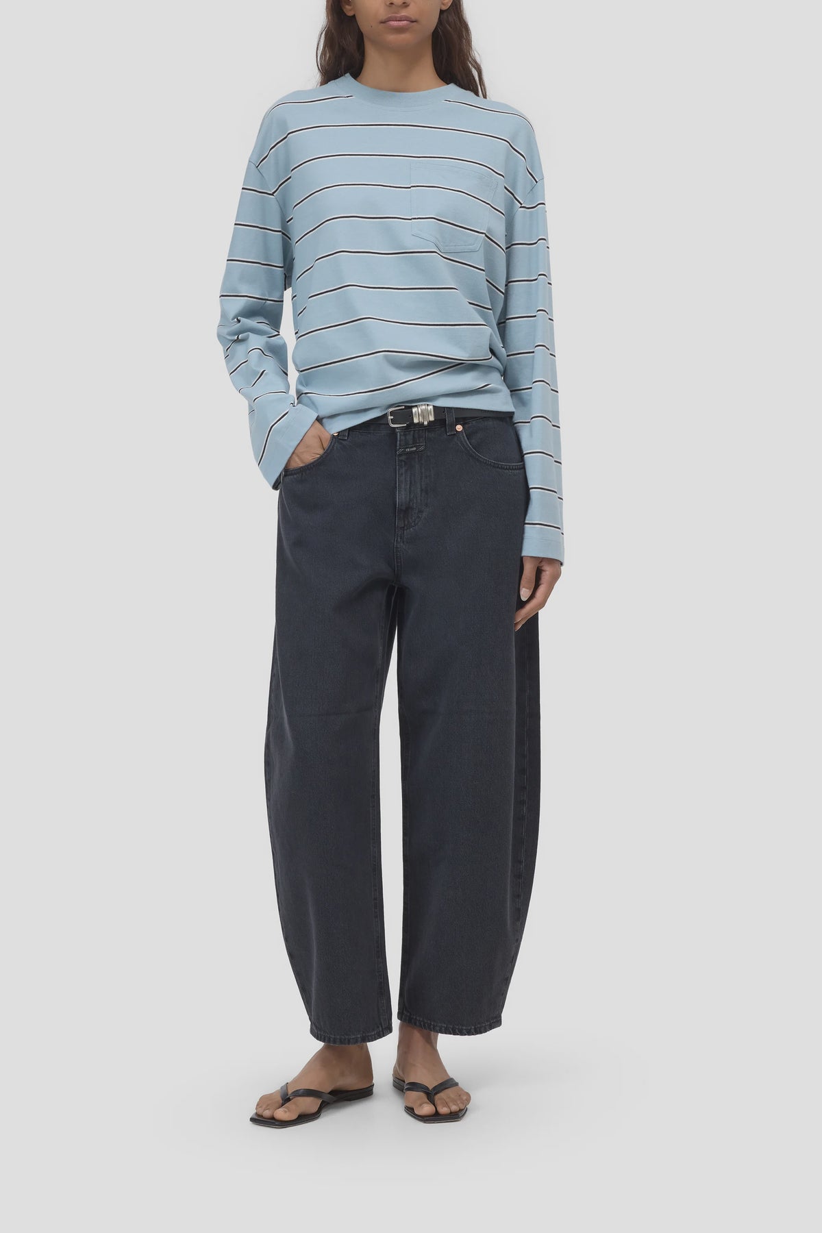 CLOSED Jazzie blue striped shirt styled with barrel-fit denim and black sandals, hands in pockets.