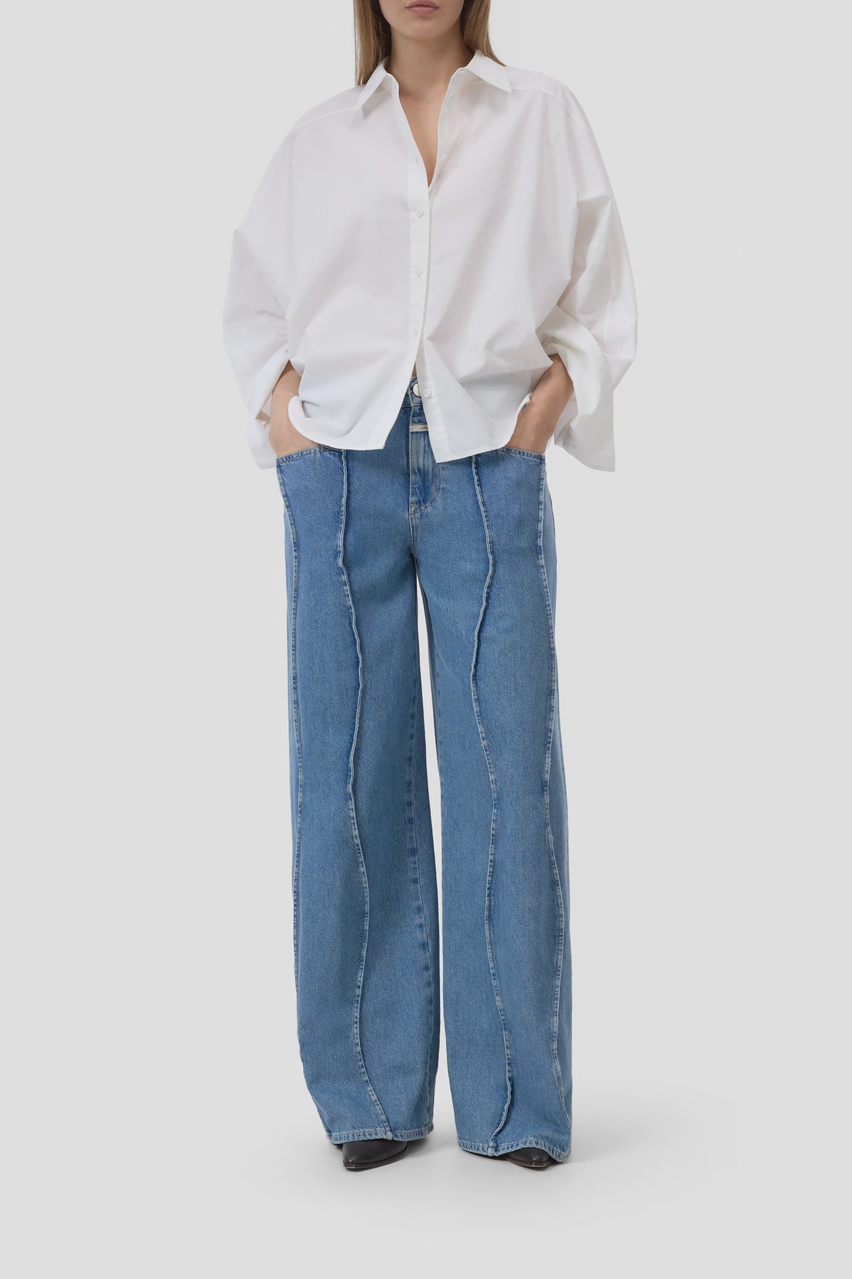 CLOSED embroidered shirt with wide-leg blue jeans featuring wavy seams, shown hands in pockets.