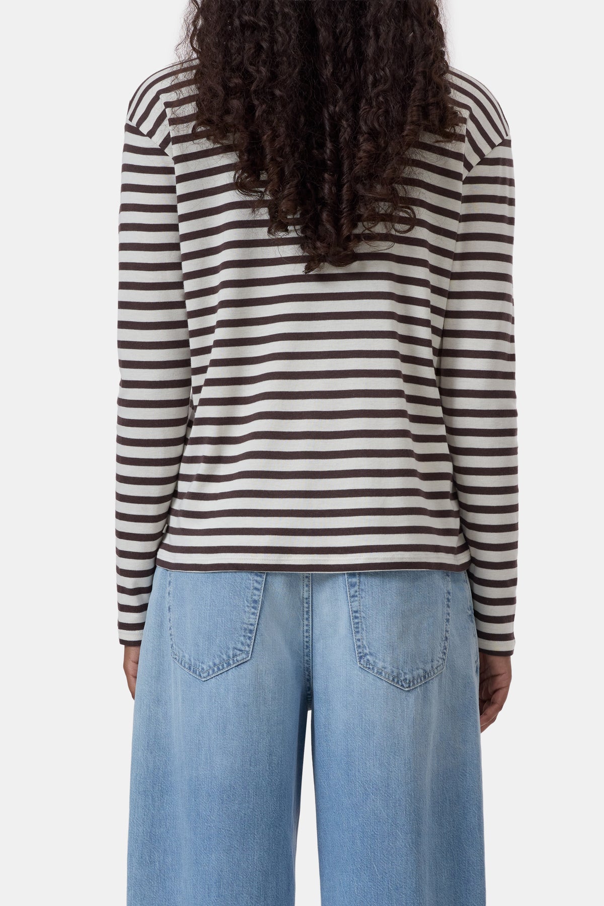 Black and white striped long sleeve tee by CLOSED with light blue jeans, shown from behind in a casual setting.