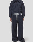 Navy Bow Tie Hoodie by CLOSED layered over white shirt with relaxed drawstring pants, casual modern look.