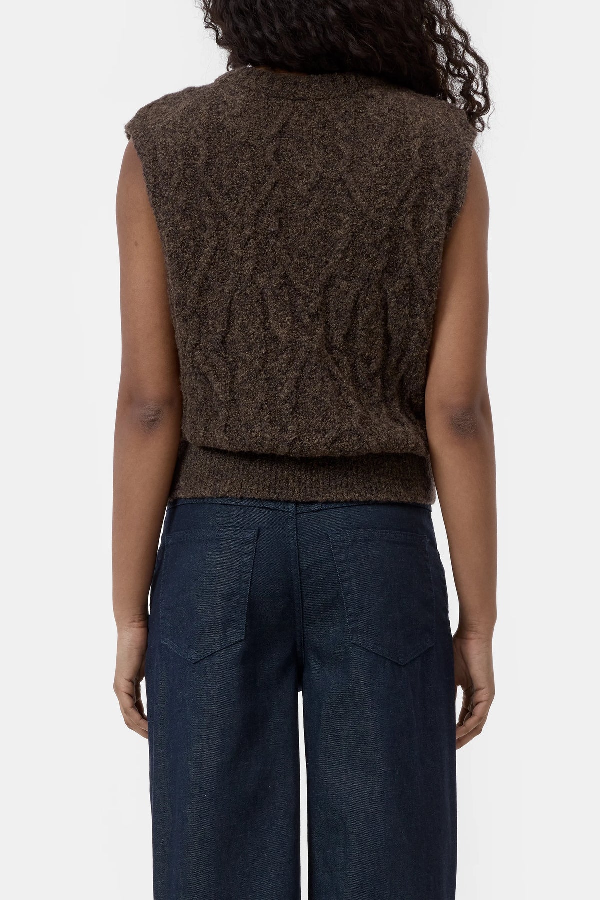 Brown cable knit CLOSED vest with crew neck, styled with dark blue jeans, back view.
