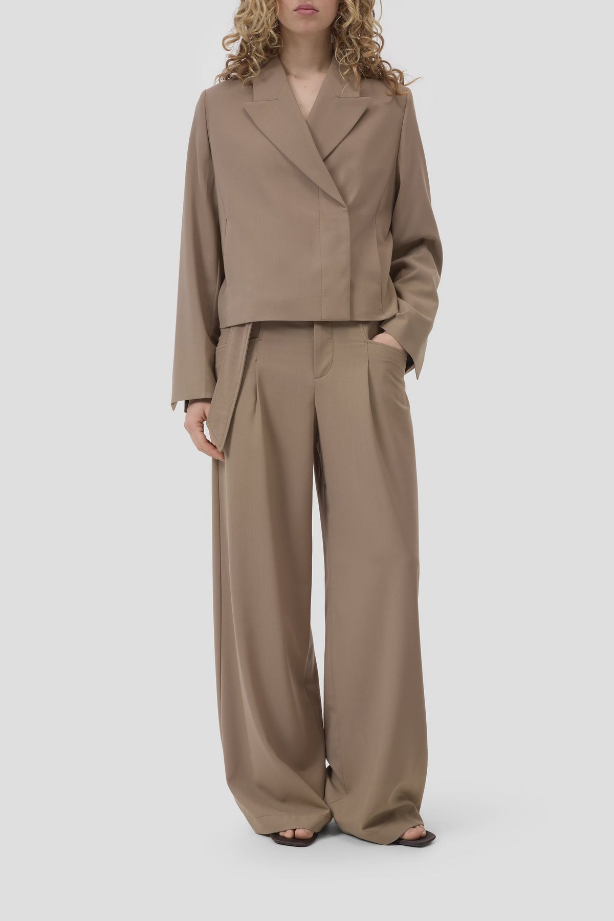 CLOSED cropped blazer and relaxed wide-leg pants in neutral tones, hands in pockets, modern tailored look.
