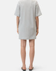 A person faces away wearing the CLOSED Felpa Dress, a loose, short-sleeved light gray cotton piece made in Portugal, paired with black open-toe sandals against a plain white background.