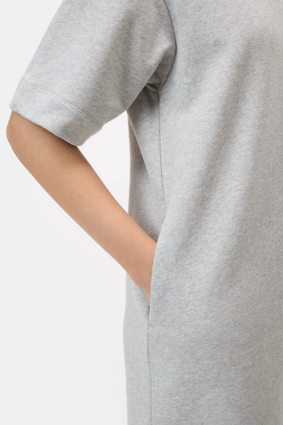 A person models the CLOSED Felpa Dress in light grey—made in Portugal from 100% cotton Felpa fabric—with a short-sleeve, shoulder to mid-thigh cut, and a hand in the side pocket, against a plain white background.