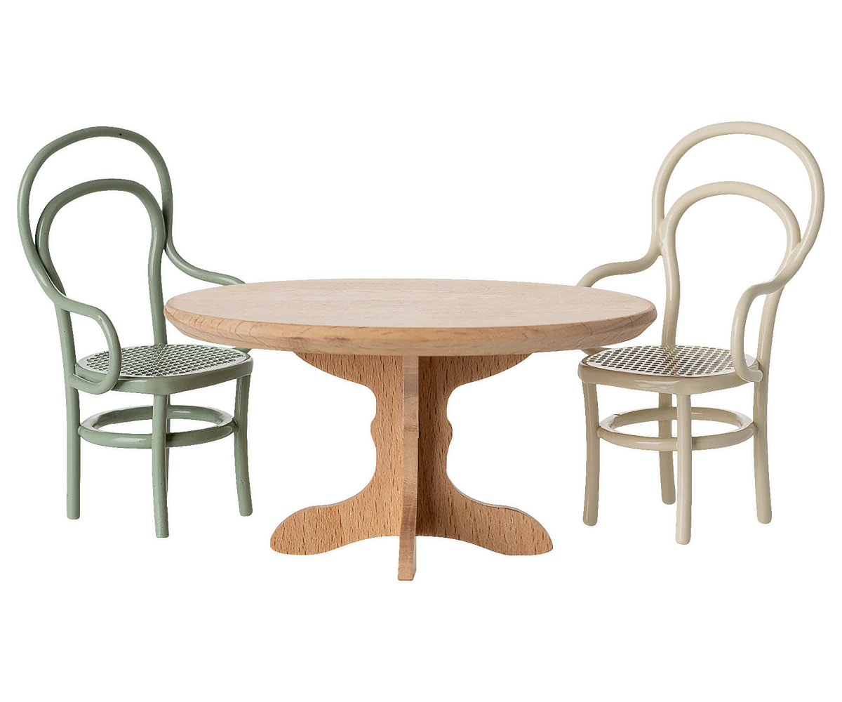 The Maileg Oval dining table by Maileg, paired with two bentwood chairs—one green, one cream—shows off its fine wooden quality and invites a cosy dinner party mood against a plain white background.