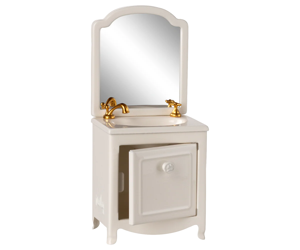 The Maileg Sink Dresser is a small white vanity cabinet with an open door, gold faucets, and an attached mirror—perfect for adding classic farmhouse elegance to any dollhouse or miniature setting.