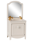 The Maileg Sink Dresser is a small, white farmhouse bathroom vanity with a cabinet door, gold faucet and handles, an attached mirror with rounded top corners, and a classic bathroom sink.
