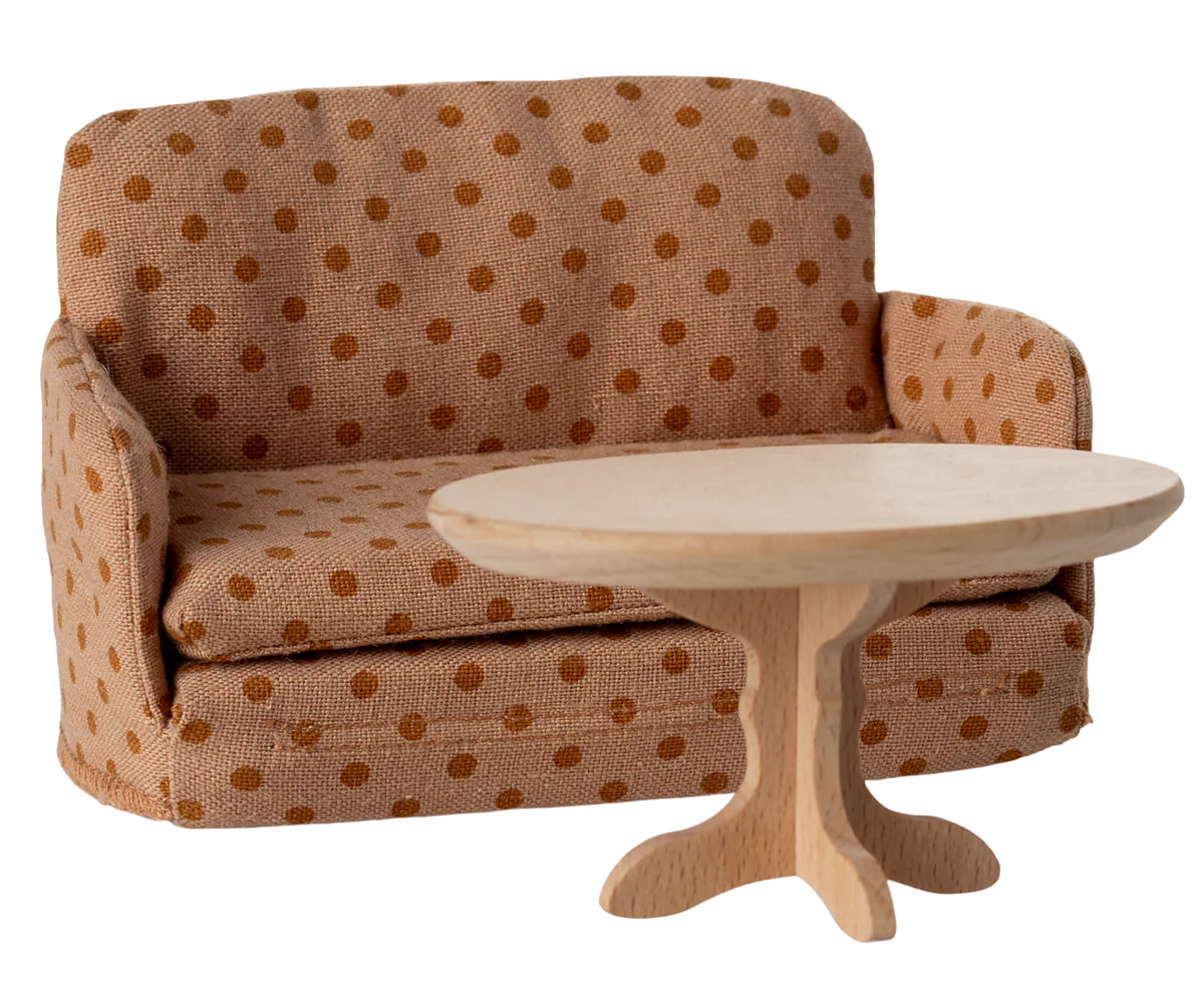 A Maileg Sofa Bed in brown polka-dots stands behind a small round wooden table, both perfect for a Maileg dollhouse living room or toy set, shown on a plain white background.