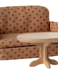 A Maileg Sofa Bed in brown polka-dots stands behind a small round wooden table, both perfect for a Maileg dollhouse living room or toy set, shown on a plain white background.