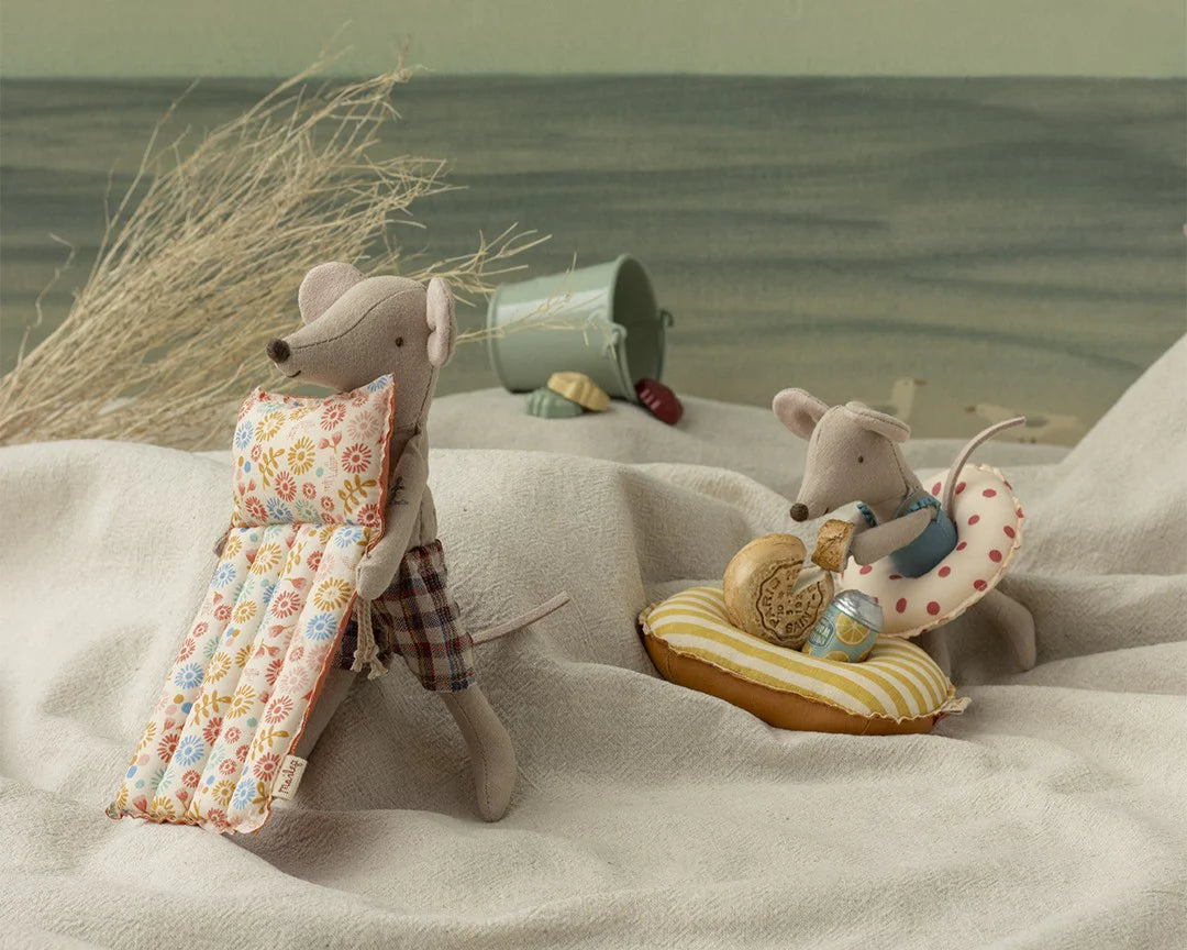 The Maileg Beach Mouse w/ Air Mattress Dad by Maileg features Dad Mouse in plaid shorts with a floral air mattress, ready for beach play. The set includes beach accessories and a sea backdrop for imaginative adventures.