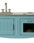 The Maileg Kitchen is a charming blue miniature playset featuring a silver sink and faucet, two stove burners, an oven door with a tiny item inside, and a left cabinet—perfect for any mouse house setup.