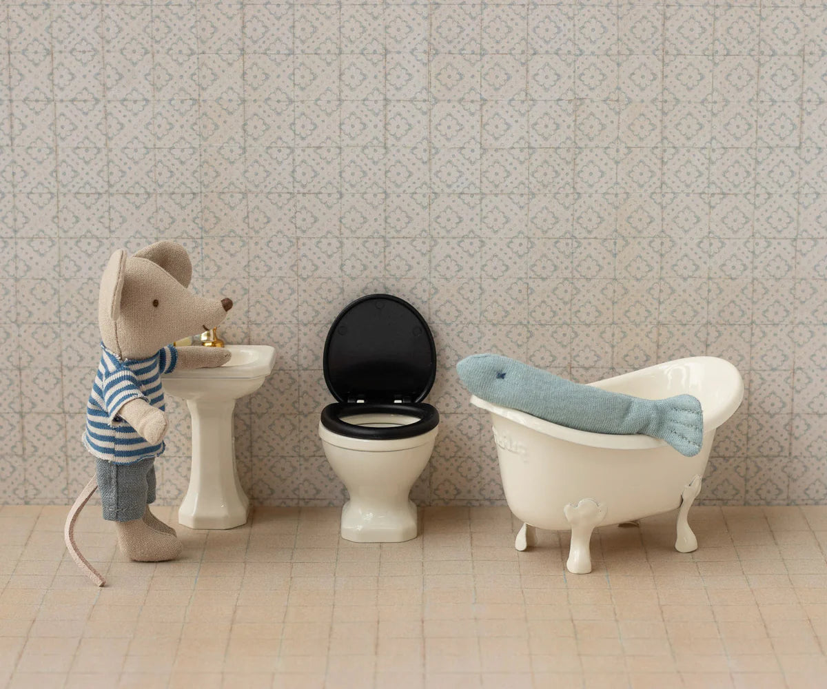 A Maileg toy mouse in a striped shirt stands by a sink and toilet, while a plush seal lounges in a clawfoot tub—creating the perfect dollhouse bathroom scene to inspire imaginative play with the Maileg Fishing Set.