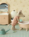 The Maileg Big Sister Mouse, Matchbox, wears pink pajamas and stands by a pink bathtub with sponge, sink and mirror, toilet, green watering can, bottle, and patterned floor—ideal to pair with soft bedding or matchbox toy accessories.