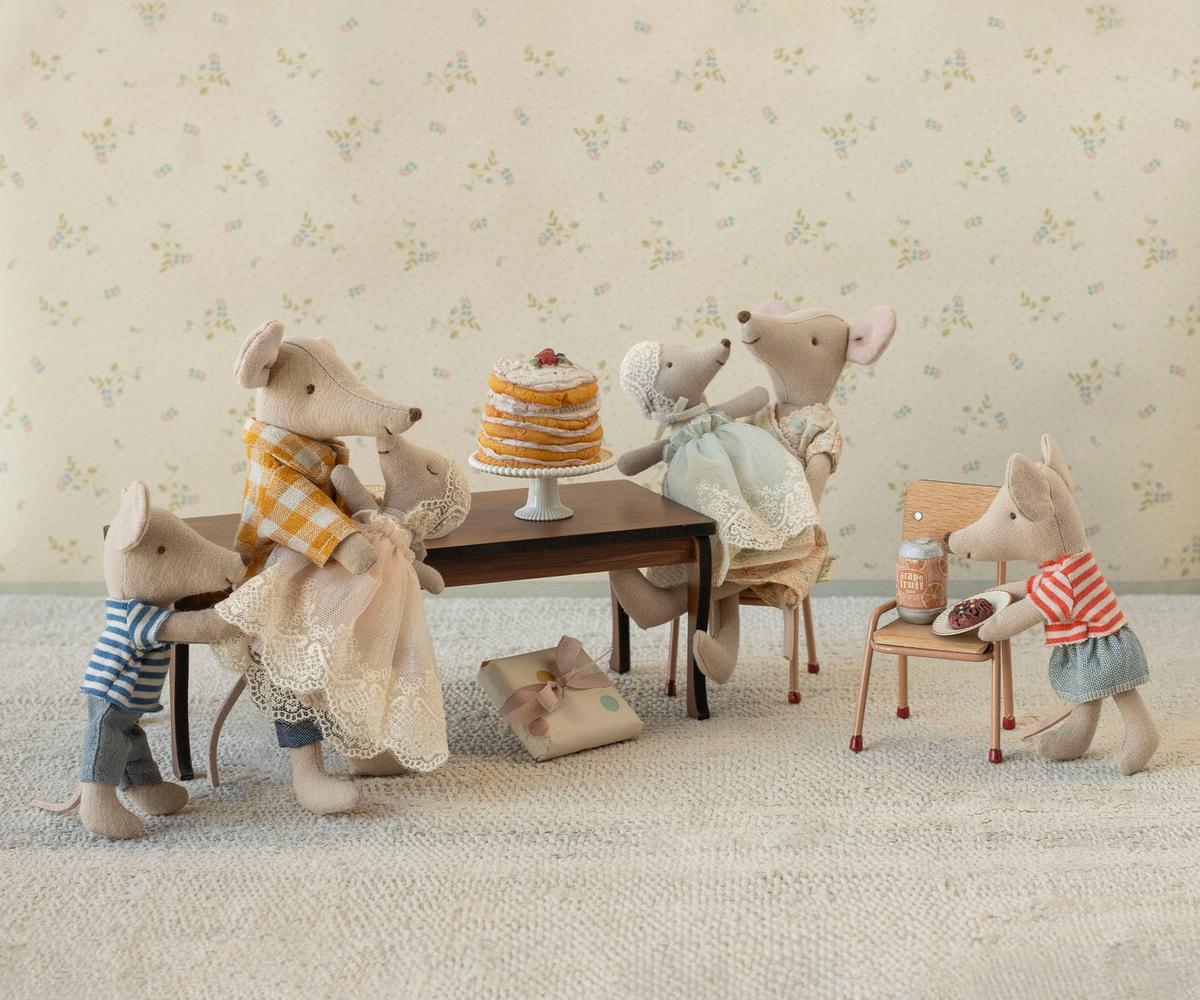 Five Maileg mice, dressed in vintage-style clothes, gather around a table with the Maileg Party cake and a wrapped gift. Two sit on chairs, two stand beside the table, and one stands on a stool holding syrup. Brand: Maileg.