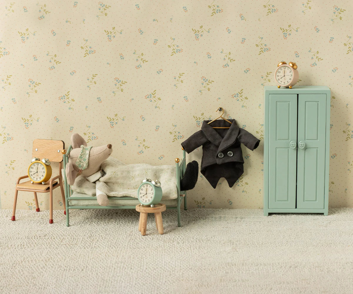 Maileg toy mouse tucked in bed with green wardrobe and accessories, styled in Mouse Hole Farmhouse bedroom setting.