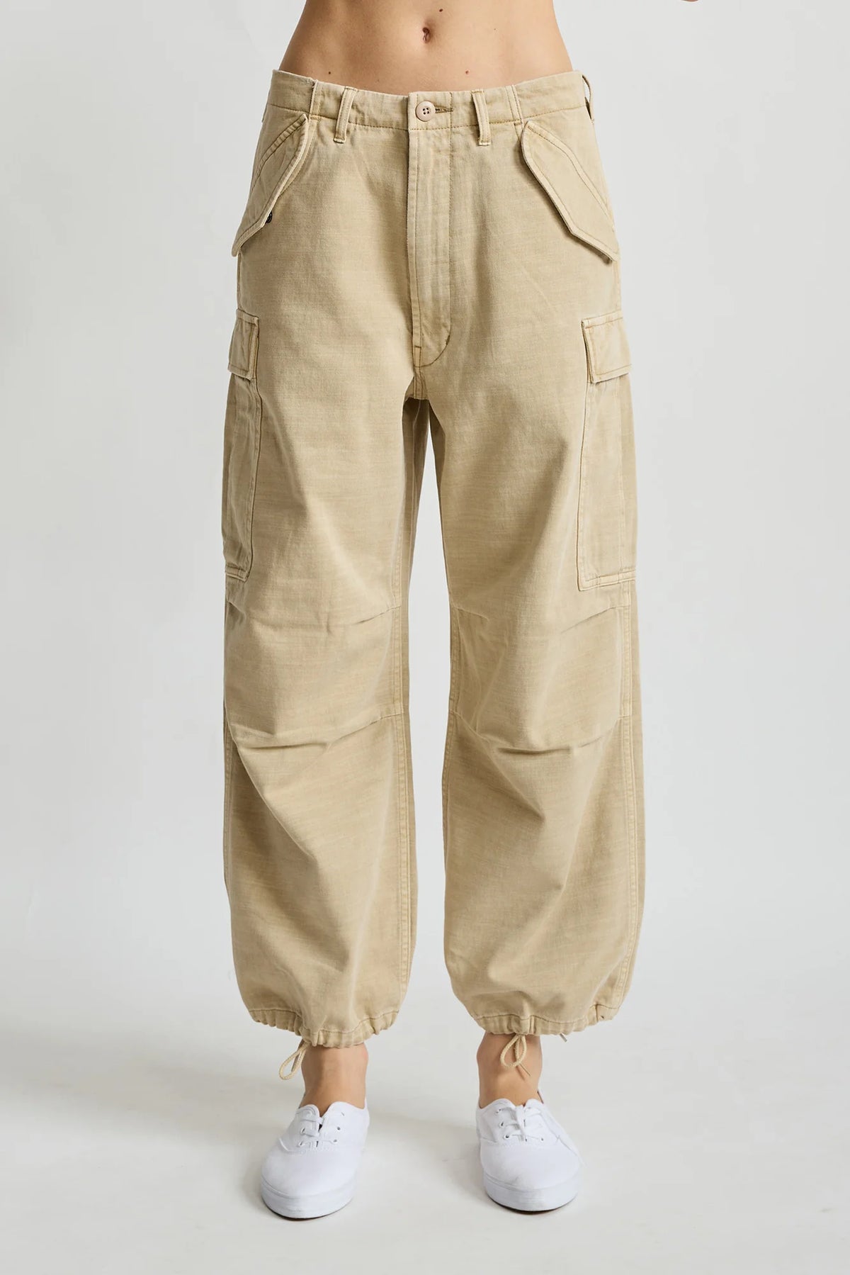Denimist cropped cargo pants with utility pockets and drawstring ankles styled with white sneakers on neutral backdrop.