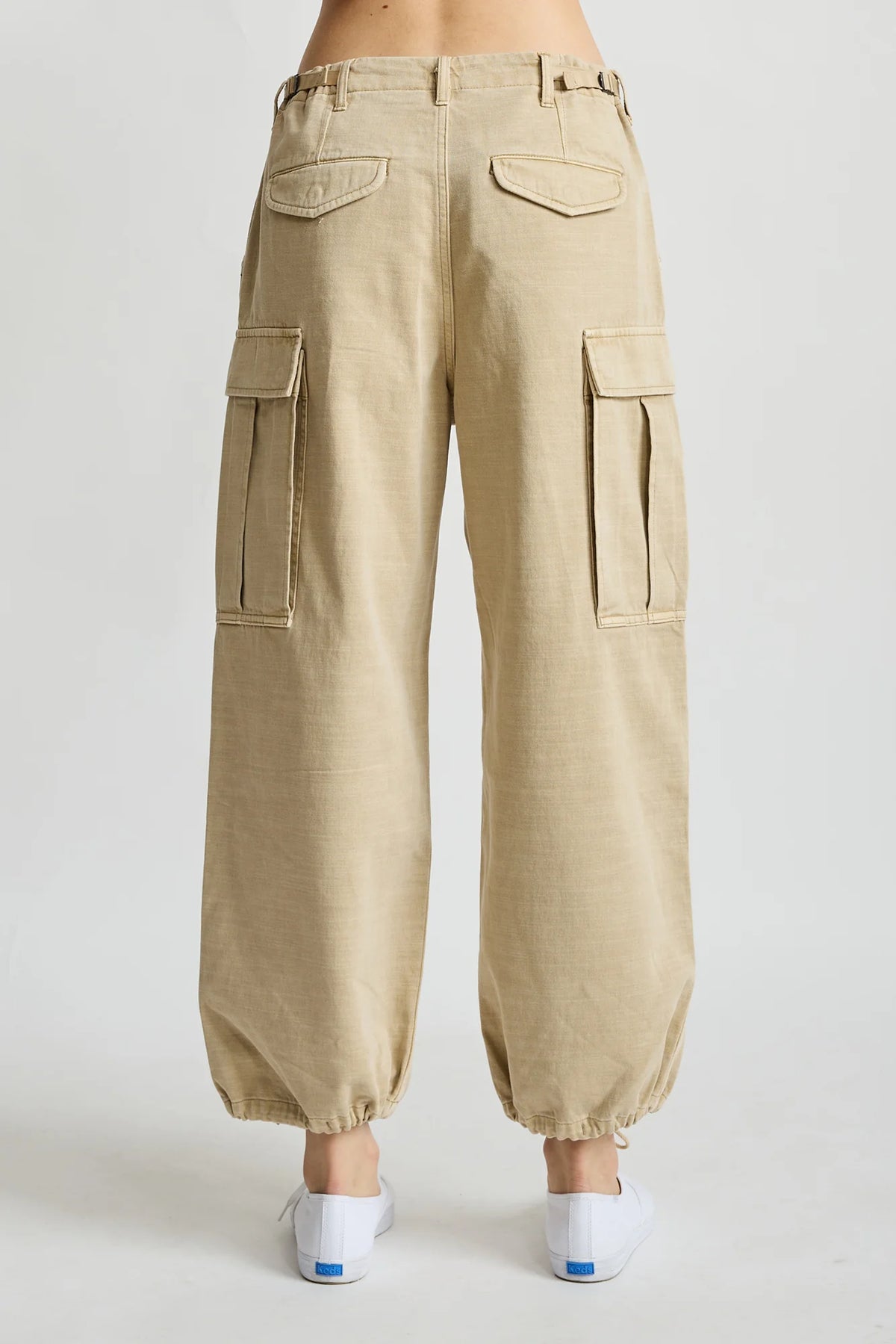 Beige Denimist cropped cargo pants styled with white slip-on shoes, shown from the back.