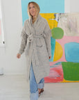 Cali Fringe Cardigan in grey merino wool with fringe shoulders and tie waist, styled over jeans.