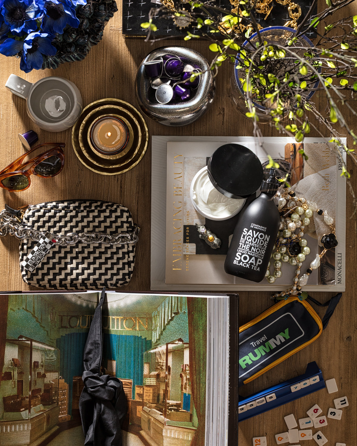 Eclectic tabletop scene with books, flowers, games, and leather purse; cozy Bungalow Furniture & Accessories style.