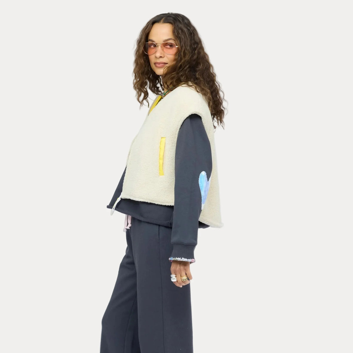 Cream Kerri Rosenthal Coze Magoze vest styled over dark clothing, shown in a modern, minimal setting, side profile view.