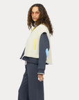 Cream Kerri Rosenthal Coze Magoze vest styled over dark clothing, shown in a modern, minimal setting, side profile view.
