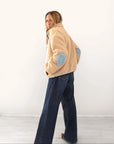 Kerri Rosenthal Coze Magoze jacket in tan with light blue Imperfect Heart elbow patches, paired with dark denim jeans.