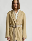 Denimist deconstructed blazer with belt in grey, styled over a striped shirt and jeans against a minimalist backdrop.