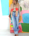 Kerri Rosenthal Maxwork Cable Sweater in cream, styled casually before a colorful abstract artwork.