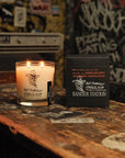 Faire Anti-Pumpkin soy candle in a glass jar next to its black box on a wooden table.