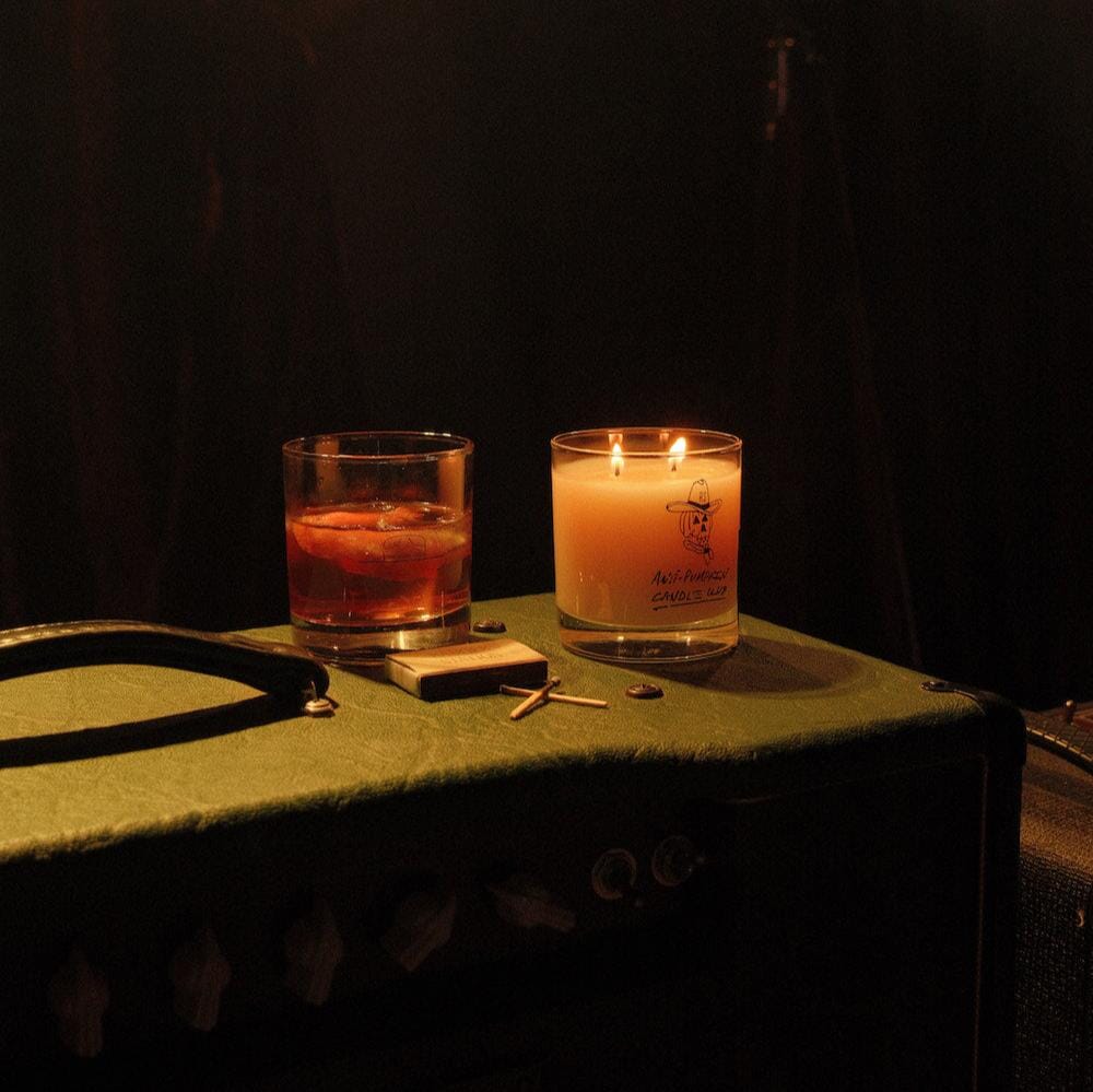 Anti-Pumpkin candle and cocktail in rocks glass resting on a green amplifier.