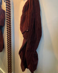 Free City Biggy corduroy pants in dark brown, hanging by a spiral-carved mirror frame.