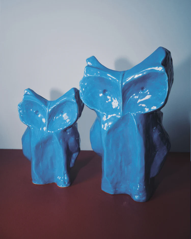 Pair of blue Serax Owl vases on a reddish-brown surface, minimal backdrop, Bungalow Furniture &amp; Accessories.