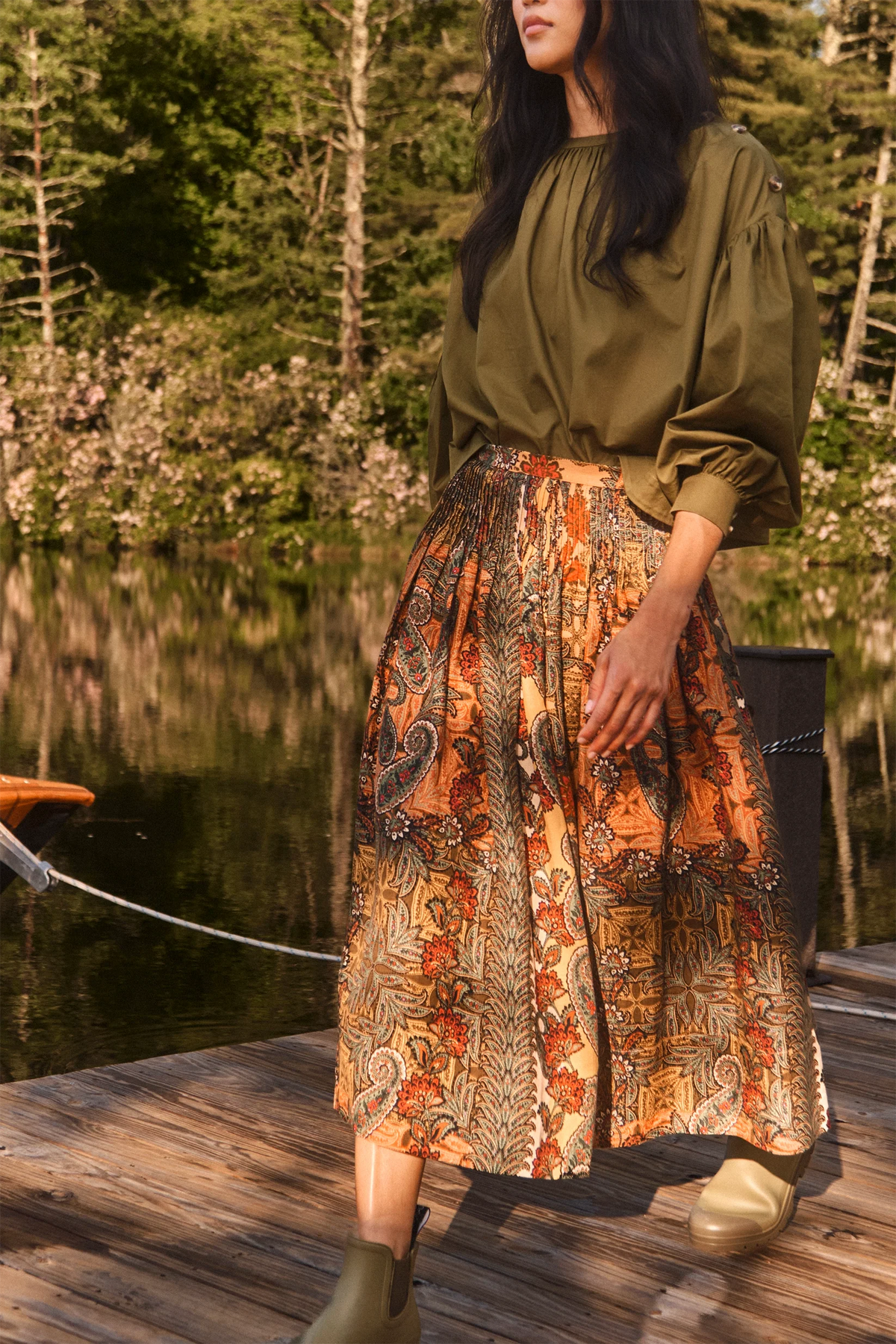 Fallon Skirt by Hunter Bell NYC styled with olive blouse and boots on a lakeside dock, natural outdoor setting.