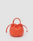 Bright orange Clare Vivier Emma Top Handle bag in Italian nappa leather with drawstring on light background.