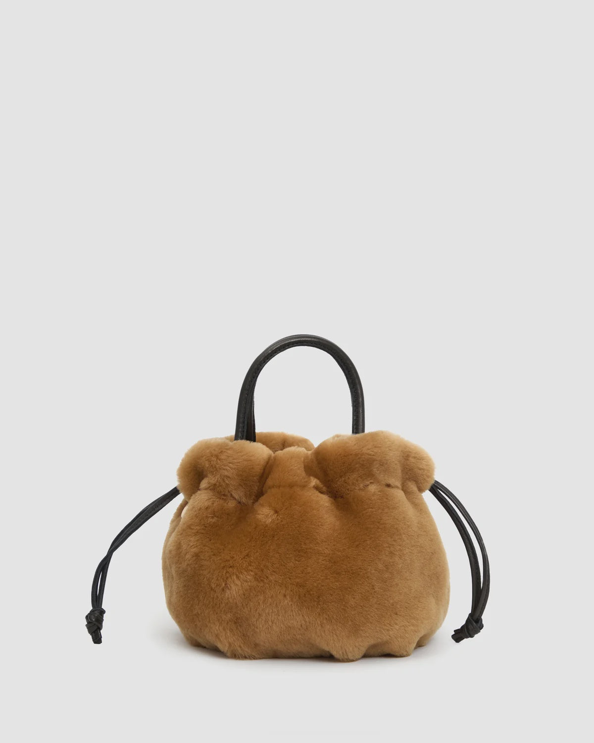 Tan shearling drawstring pouch with black leather handle and side cords by Clare Vivier.