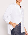 Someone wears the BROCHU WALKER EVERYDAY SHIRT in a relaxed fit with rolled sleeves, paired with dark blue jeans, one hand in their pocket and a gold bracelet on their wrist.