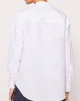 A person is seen from behind in the BROCHU WALKER EVERYDAY SHIRT, a relaxed-fit top with buttoned cuffs, paired with dark pants. The shirt drapes comfortably as they slightly turn their head to the side.