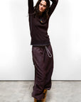 Free City Matte Satin Loose Drawcord Biggy Pant in Chocolate Rabbit, styled with a dark top, model raises arms.