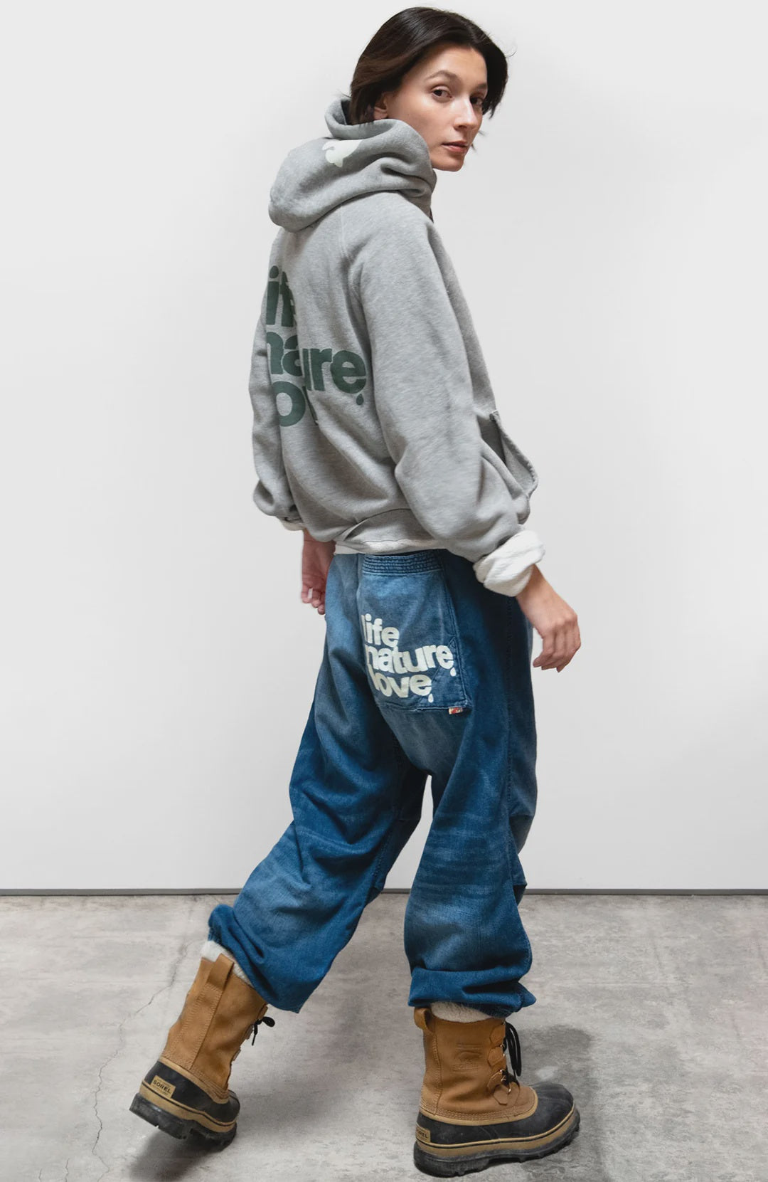 Free City LNL Backprint Fluff Pullover Hoodie in blue, styled with jeans and boots, model glancing over shoulder.
