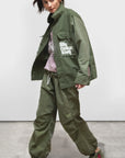 Free City Workshop Biggy Pant in gray styled with a green jacket and pink hoodie indoors at Bungalow Furniture.