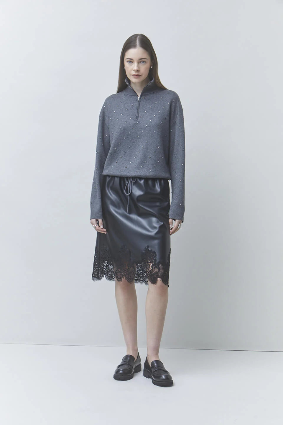 Pristo knit rhinestone sweater by SUNCOO styled with a black lace-hem skirt, shown in a modern, bright setting.