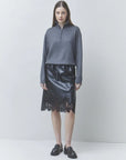 Pristo knit rhinestone sweater by SUNCOO styled with a black lace-hem skirt, shown in a modern, bright setting.