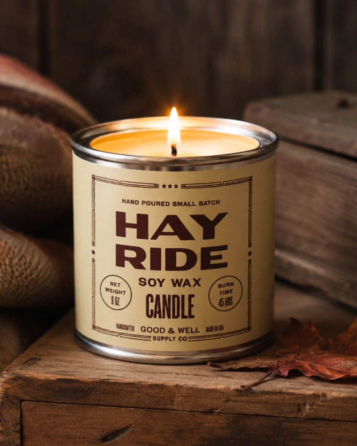 Faire Hay Ride soy candle by Bungalow Furniture on wood with a leaf and burlap sack for a cozy autumn accent.