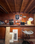 Bungalow Furniture & Accessories workshop featuring modern decor, tools, and the Faire Every Damn Day Camp Flag.