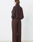SUNCOO Dona chocolate brown jacket and wide-leg pants seen from the back, modeled by a woman with short brown hair.