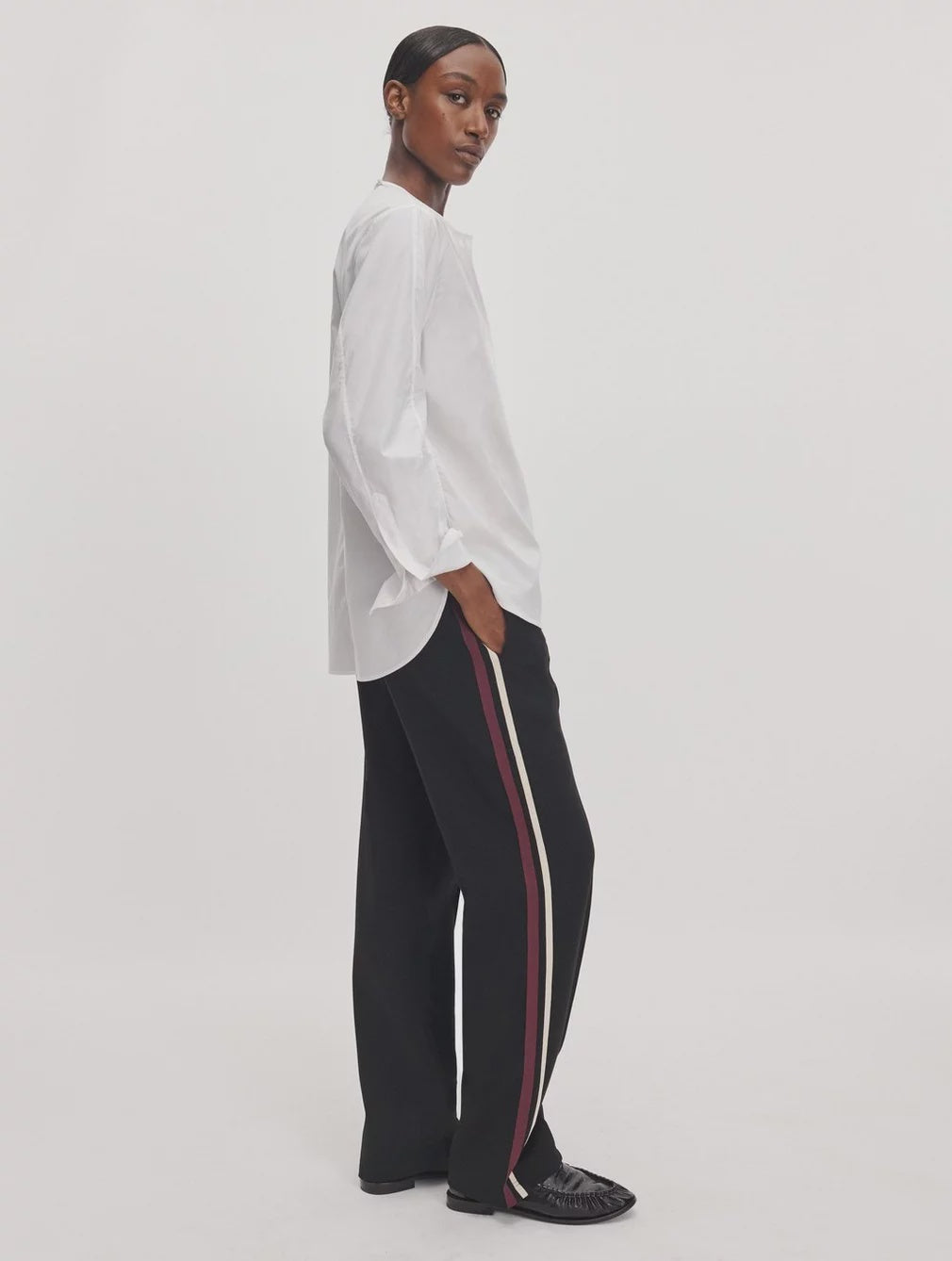 Rag &amp; Bone Irina Ponte track pants in black with red and cream side stripes, styled with a white button-down shirt.