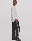 Rag & Bone Irina Ponte track pants in black with red and cream side stripes, styled with a white button-down shirt.