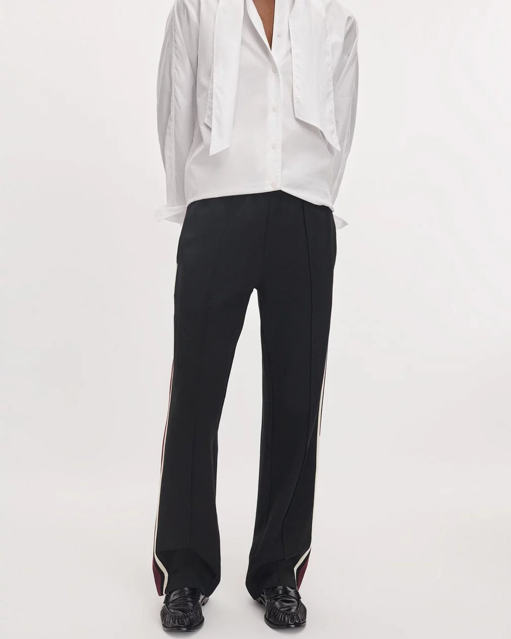Rag &amp; Bone Irina Ponte mid-rise wide-leg track pants in black with white and burgundy side stripes, paired with a shirt.