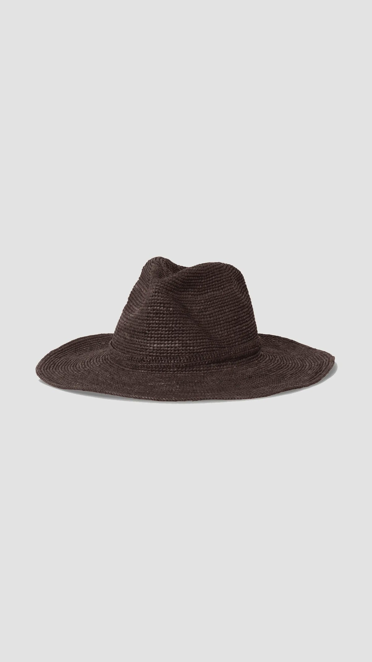 The Sacha Hat by Janessa Leone is a wide-brimmed, dark brown Madagascar straw hat with a slightly creased crown, shown on a plain light gray background.