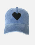 The Kerri Rosenthal Baseball Hat Heart Patch is a light blue denim cap with a large black heart embroidered on the front, displayed on a plain white background.
